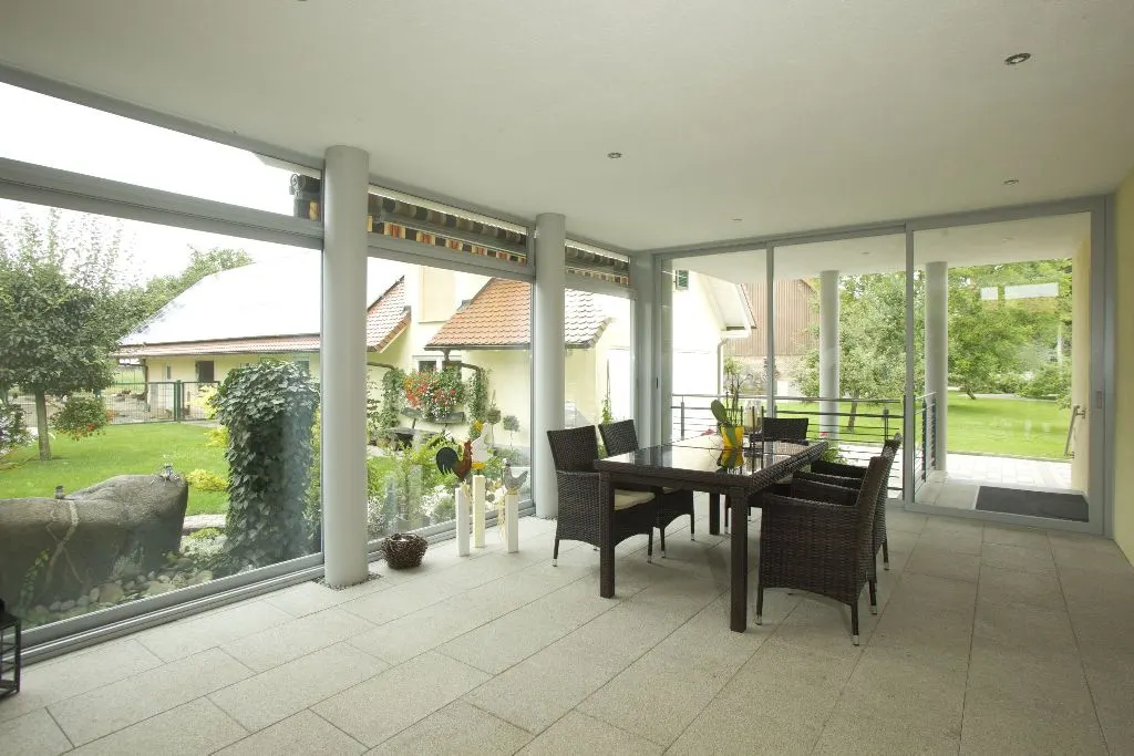 Sommergarten aus Glas an einem Wohnhaus mit umlaufenden Schiebeelementen